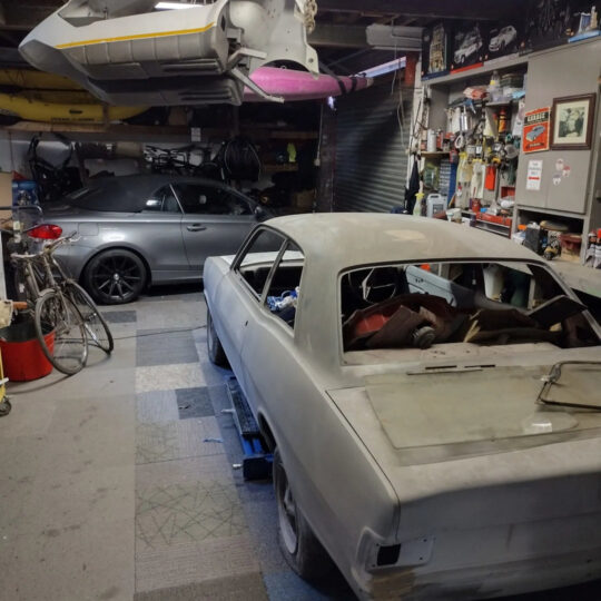 Classic car restoration project in a workshop garage filled with tools and parts