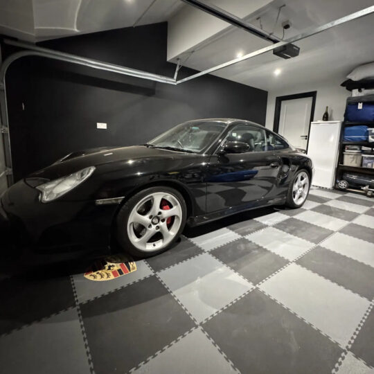Black Porsche in a modern garage with black and white Duramat interlocking floor tiles
