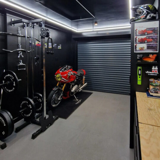 Modern man cave garage with motorcycle, gym equipment and LED strip lighting