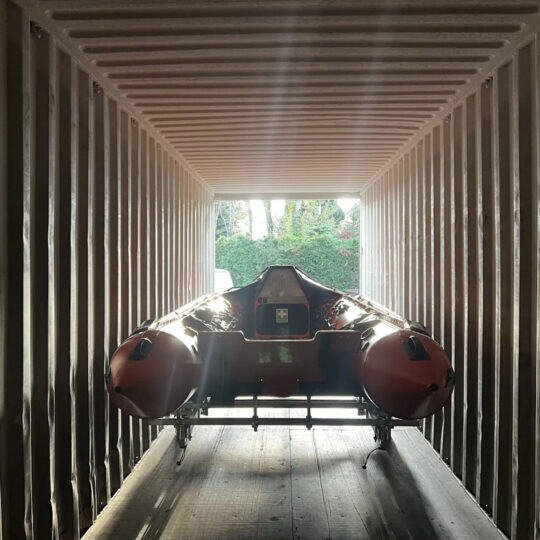Inflatable RIB boat stored on a trailer inside a timber-framed shelter