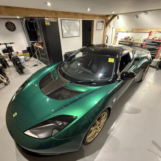 Green TVR sports car with gold wheels parked in a residential garage