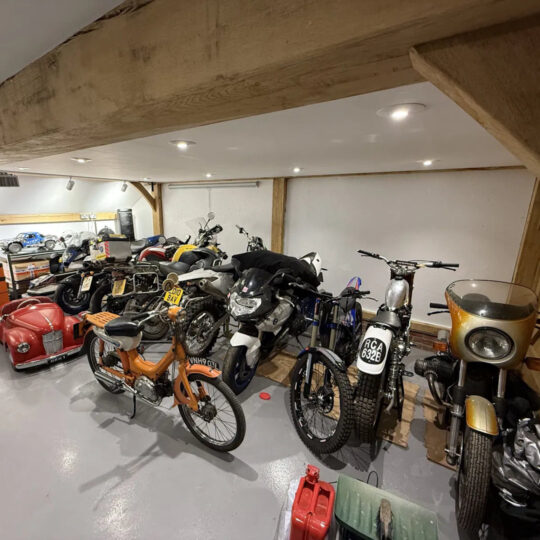 Collection of vintage motorcycles stored in a timber-beamed barn garage