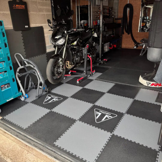 Triumph motorcycle in a garage on grey and black Duramat interlocking floor tiles