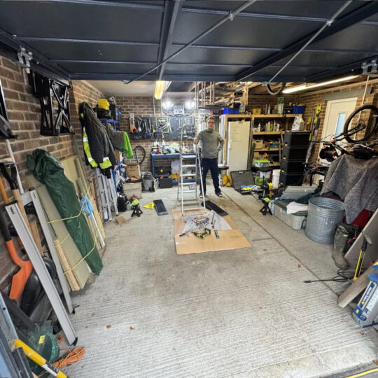 Garage workshop being set up with tools and equipment on a concrete floor