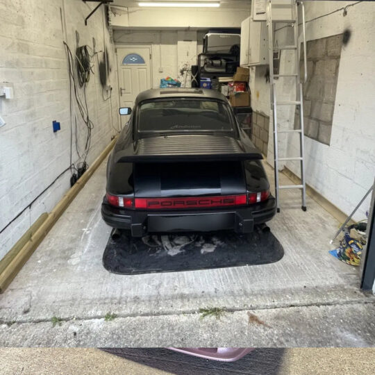 Black Porsche 911 parked in a residential garage on a concrete floor