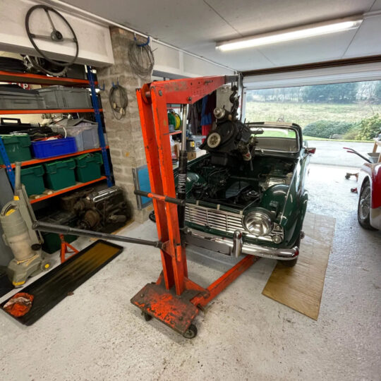 Classic Mini on a car lift in a well-equipped workshop garage with tool shelving